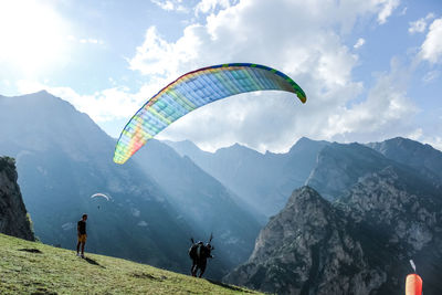 People paragliding on mountain peak against sky