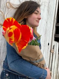 Side view of teenage girl with bouquet standing outdoors