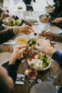 Male friends serving food at dining table during dinner party in patio