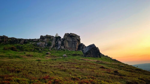 Scenic view of rocks against clear sky during sunset