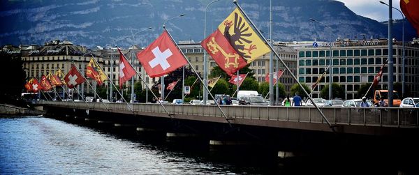Various flags on bridge over river in city