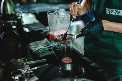 Midsection of man pouring wine in glass