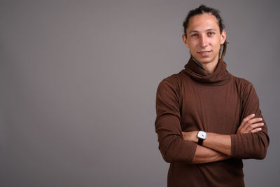 Portrait of smiling man standing against gray background