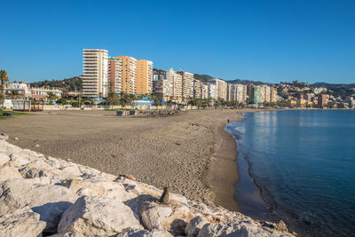 View of beach and buildings against clear blue sky