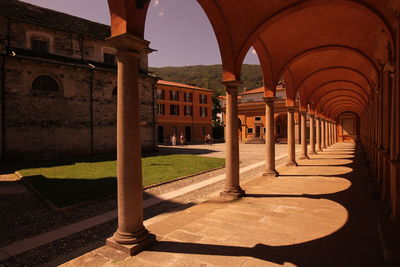 Empty colonnade in church by bell tower against sky