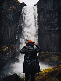 Rear view of person standing against waterfall