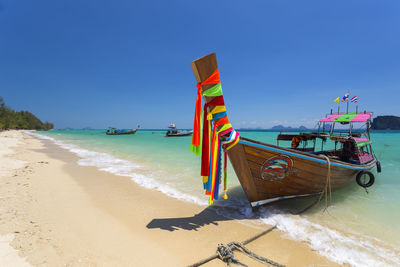 Longtail boat at beach against clear sky