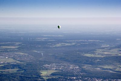 Distant view of hot air balloon flying over green landscape