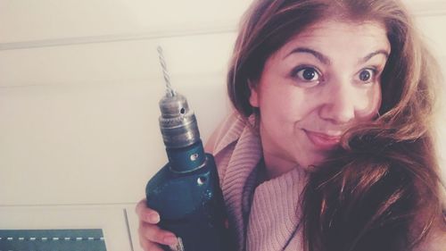 Portrait of young woman holding camera at home