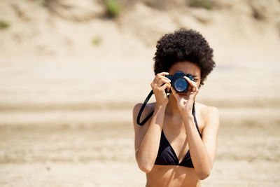 Woman photographing through camera at beach