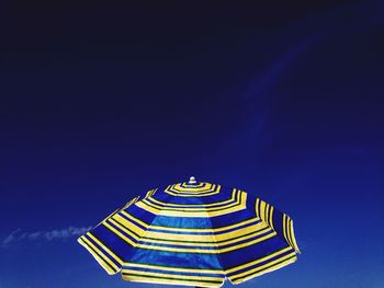 Low angle view of parasol against blue sky