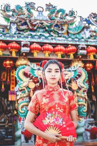 Portrait of teenager holding hand fan standing at temple