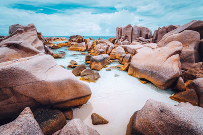 Rocks in sea at beach against sky