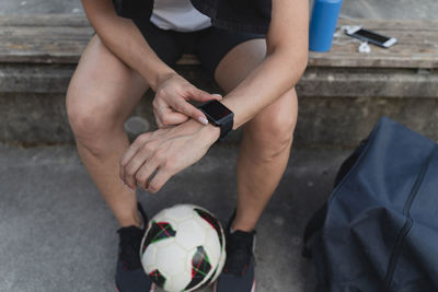 Woman with soccer ball checking time in smart watch