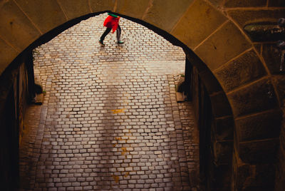 Rear view of man standing by wall of building