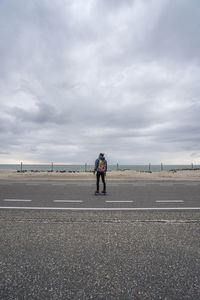 A man with long hair skating on a empty road in europe