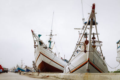 Fishing boat moored at harbor against sky