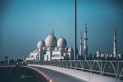 Road by mosque against clear blue sky