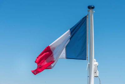 French flag on the pole over a blue sky.