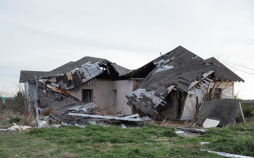 Abandoned house on field against sky