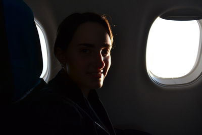Portrait of smiling woman sitting by window in airplane