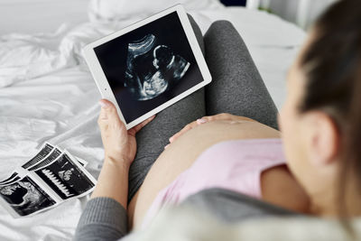 Midsection of woman using mobile phone on bed