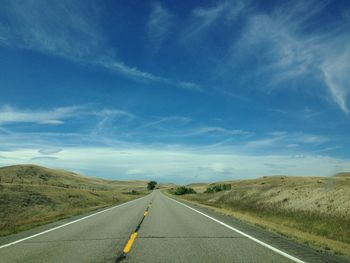 Surface level of empty road against cloudy sky