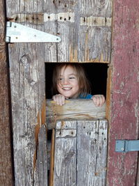 Young boy peeking out of old door