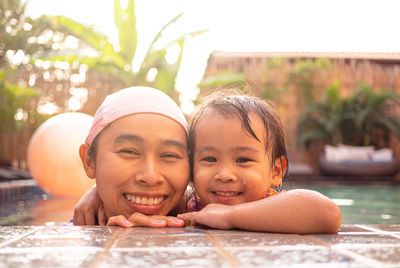 Close-up portrait of woman with daughter smiling in swimming pool