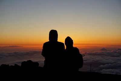 Silhouette people looking at sunset