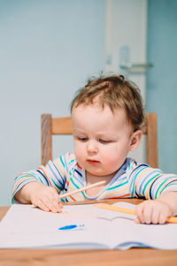 Portrait of boy sitting on table at home