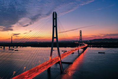 Bridge over river against sky during sunset