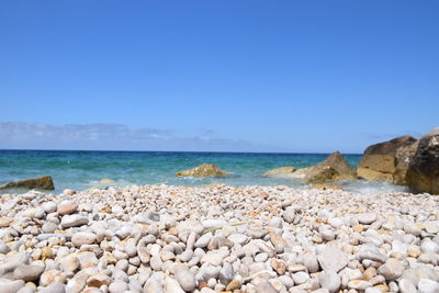 Pebbles on beach against clear sky