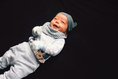 High angle view of cute smiling toddler lying against black background