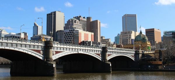 Princes bridge over yarra river by buildings against sky