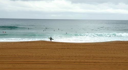 High angle view of man holding surfboard at beach