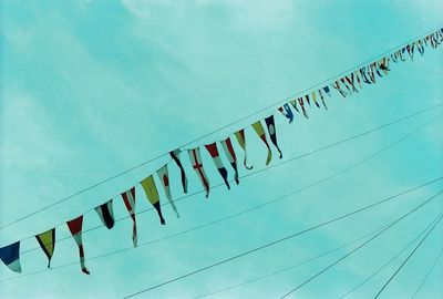 Low angle view of flags hanging against blue sky