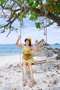 Full length of woman siting on swing at beach