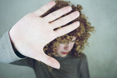 Young woman showing stop gesture against gray background