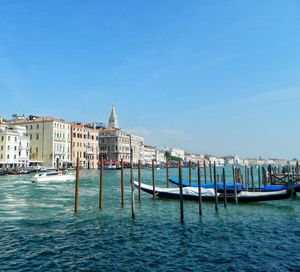 View of boats in canal by buildings against sky