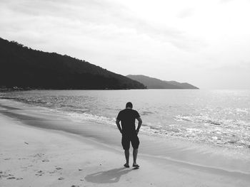 Rear view of man on beach against sky