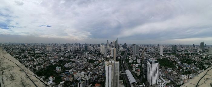 Aerial view of cityscape against cloudy sky