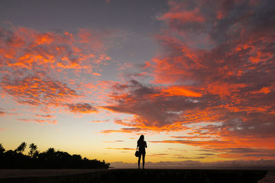 Silhouette woman standing against orange sky