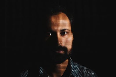 Portrait of young man against black background