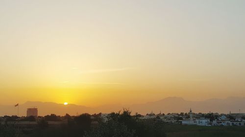 Silhouette trees and buildings against sky during sunset
