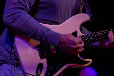 Midsection of man playing guitar