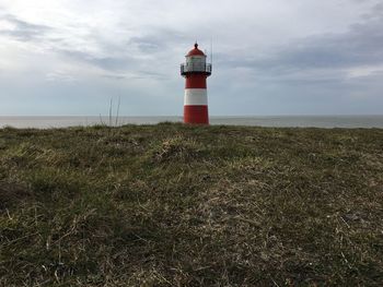 Lighthouse by sea against sky