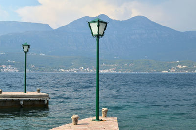 Street light by sea against mountains