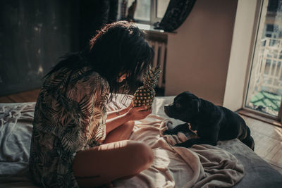 Midsection of woman with dog sitting at home