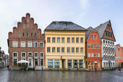 Buildings by river against sky in city